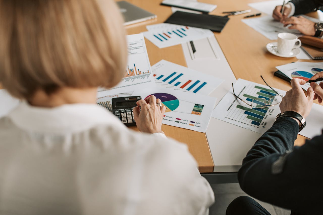 get-in-touch Overhead view of professionals discussing financial graphs and using calculators in an office setting.